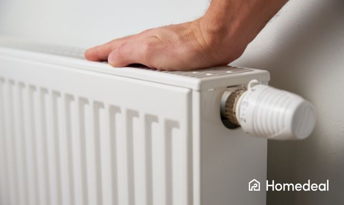 Close up van een paneelradiator met knop waar een man zijn hand op legt