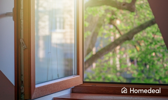 Openstaand houten draai-kiepraam met dubbel glas en zicht op groene bomen buiten.