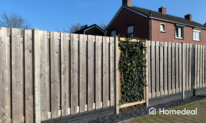 Houten schutting bij een tuin met een stukje klimop ertussen