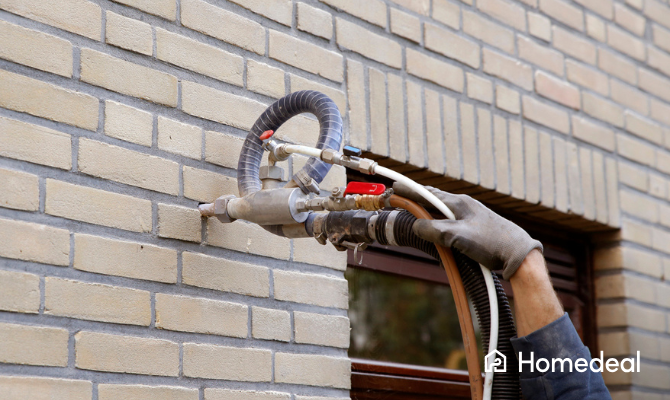 Spouwmuurisolatie wordt in gaten van spouw van een huis gespoten