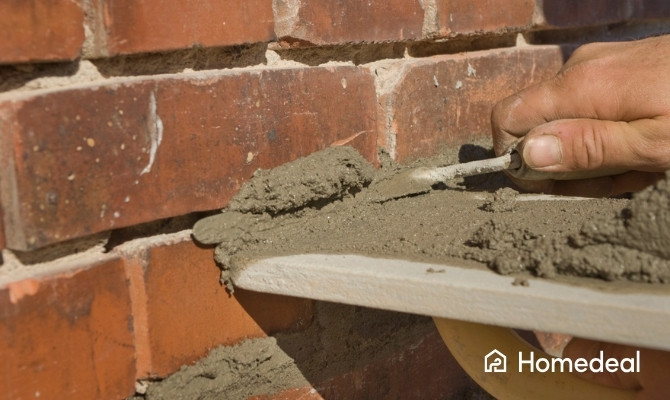 Vakman voert voegwerken uit door verse mortel aan te brengen tussen bakstenen van de gevel.