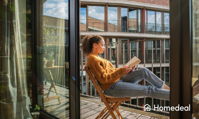 Vrouw op een stoel leest ontspannen een boek op haar balkon