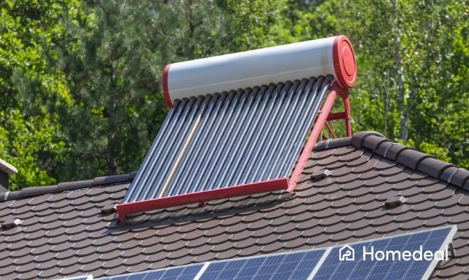 Close-up van een zonneboiler met vacuümbuizen en meerdere zonnepanelen op een pannendak.
