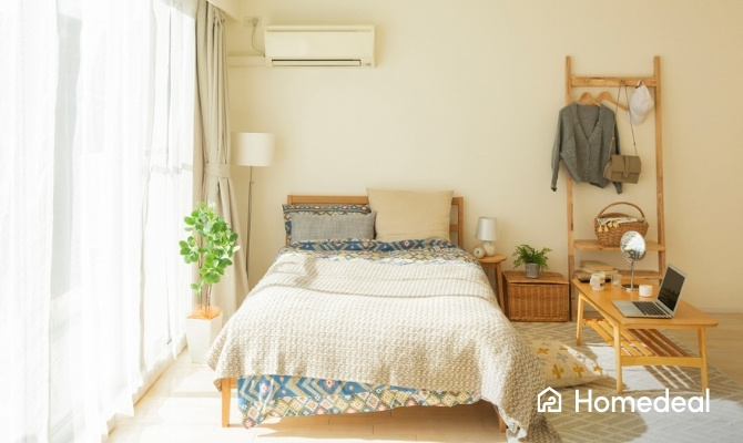 Wandairco boven het bed in een lichte, gezellige slaapkamer.