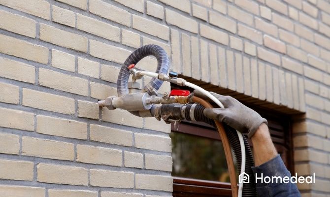 Vakman injecteert een buitenmuur met een speciaal middel om opstijgend vocht in de gevel te bestrijden.