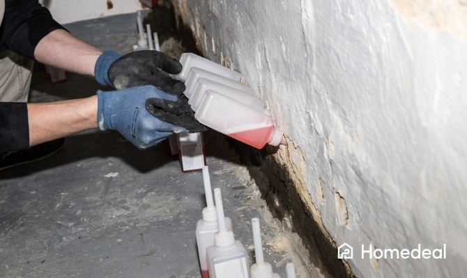 Vakman voert een muurinjectie uit in een keldermuur om opstijgend vocht te behandelen.