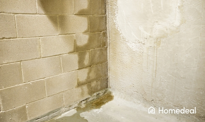 Keldermuur met duidelijke vochtplekken en verkleuring door doorslaand vocht.