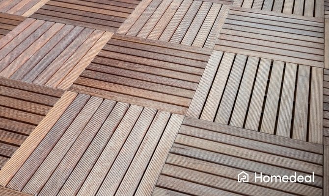 Vierkante houten terrastegels met afwisselend liggende en staande ribbels, geplaatst in patroon voor tuinbestrating.