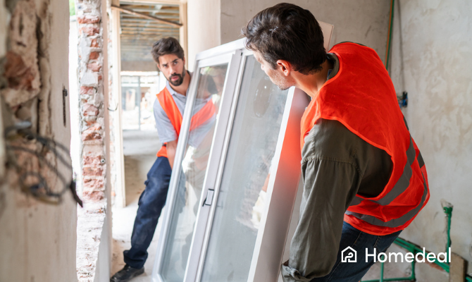 Twee glaszetters tillen een nieuw raam met driedubbel glas in een opening in de muur
