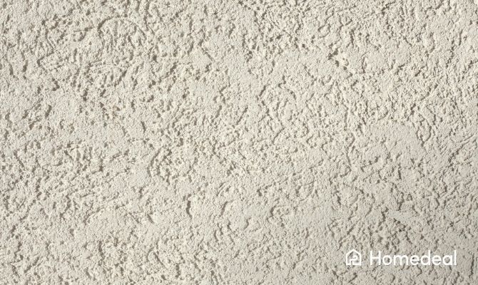 Detail van een granol muur met grove, korrelige structuur en onregelmatige sierpleisterafwerking.