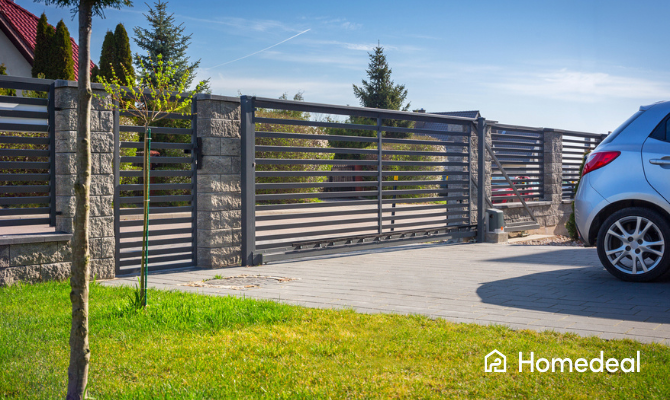 Metalen en stenen hekwerk met automatische toegangspoort bij huis