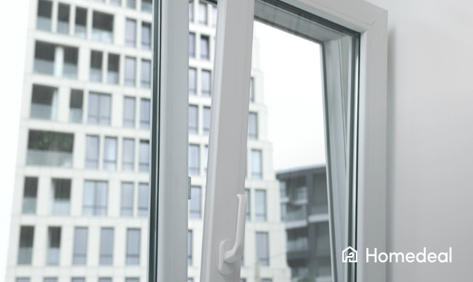Openstaand draai-kiepraam met wit profiel in een modern appartement, met zicht op omliggende gebouwen.