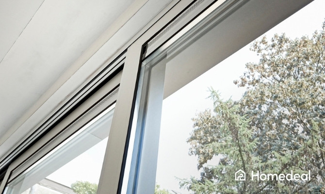 Detail van een modern schuifraam met aluminium profiel, gedeeltelijk geopend en zicht op de tuin.