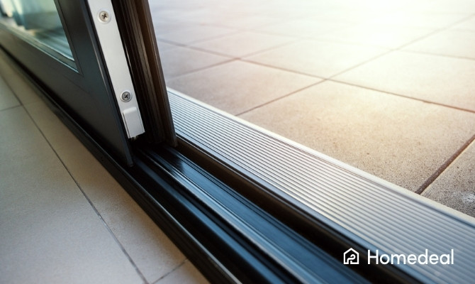 Detail van de onderrail van een schuifraam met aluminium profiel en drempelloze afwerking richting terras.