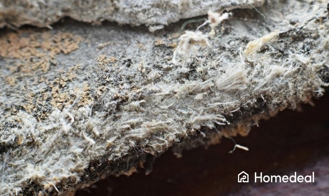 Detailopname van beschadigd asbesthoudend materiaal met zichtbare vezels, gebruikt om asbest te herkennen in oude bouwmaterialen.