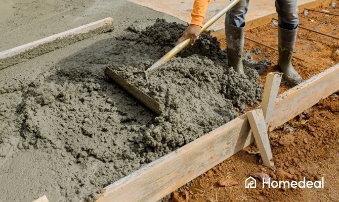 Storten en egaliseren van beton in houten bekisting voor het maken van een fundering.