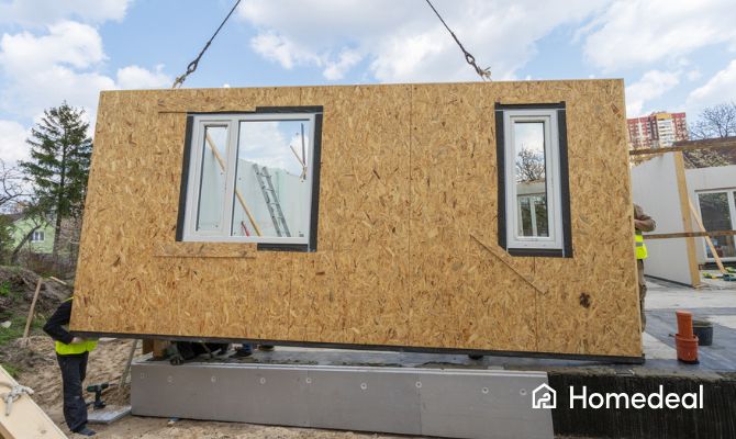 Prefab aanbouw onderdeel wordt gehesen met hijskraam