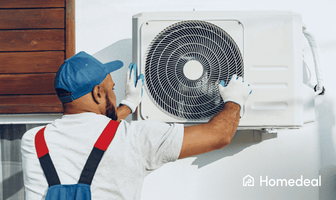 Monteur plaatst een buitenunit van een airco tegen een witte gevel.