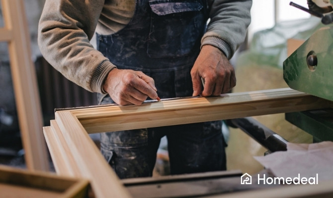 Vakman bewerkt en meet onderdelen voor houten ramen in een schrijnwerkerij.
