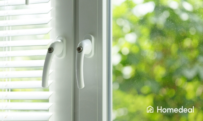 Detail van witte PVC ramen met moderne raamkrukken en dubbele beglazing, afgewerkt met jaloezieën aan de binnenzijde.