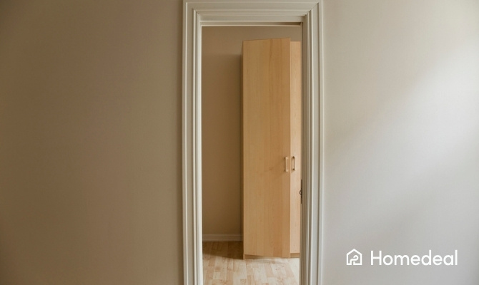 Wit deurkozijn in een afgewerkte binnenruimte met open houten deur en lichte vloer.