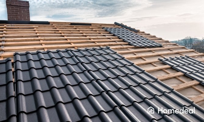 Dakrenovatie met het plaatsen van zwarte keramische dakpannen in sneldekmodel op een houten dakconstructie.