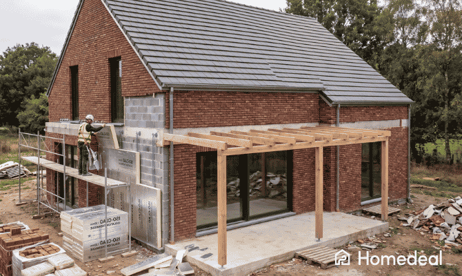 Ouvrier posant des panneaux isolants ETICS sur la facade en briques d'une maison belge - Homedeal